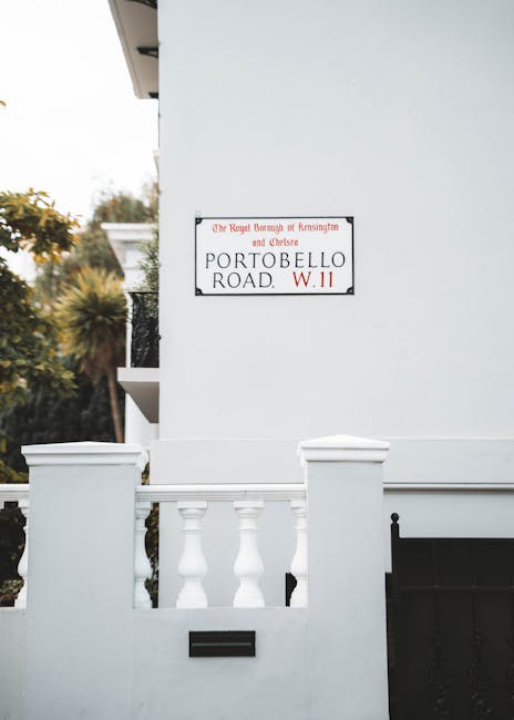 The image shows a close-up of a white residential building on Portobello Road W11 in North Kensington, with a street sign reading 'The Royal Borough of Kensington and Chelsea, Portobello Road W11.' In