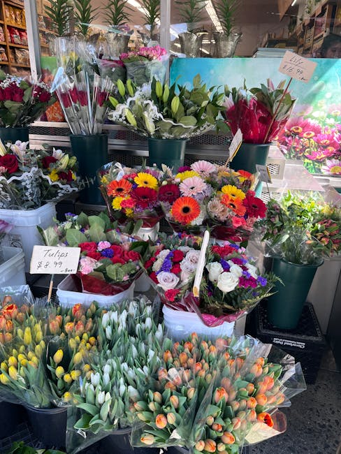 A vibrant display of floral arrangements and bouquets at a flower stall, featuring a variety of fresh flowers including tulips, daisies, roses, and lilies in bright colors such as yellow, white, pink,